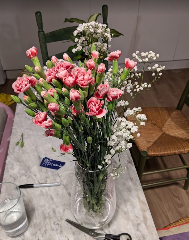a vase containing pink and white flowers sat on our dining table