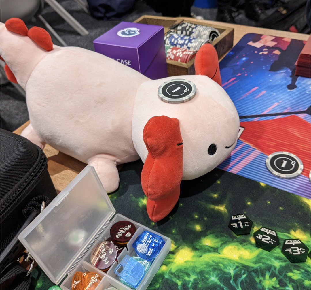 Axi the Axolotl plushie balancing a credit token on his head.